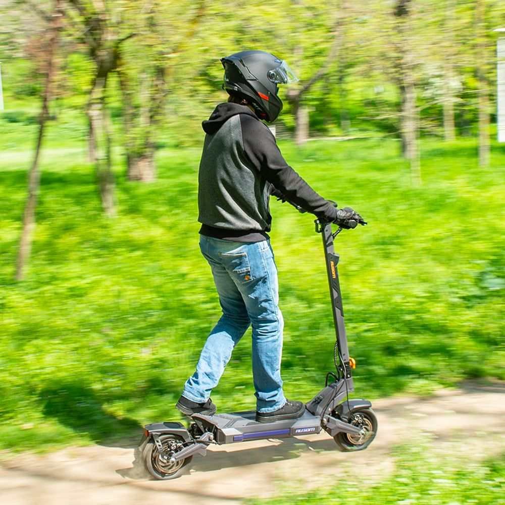 Rider on the Ausom DT2 Pro electric scooter on a park trail wearing a helmet