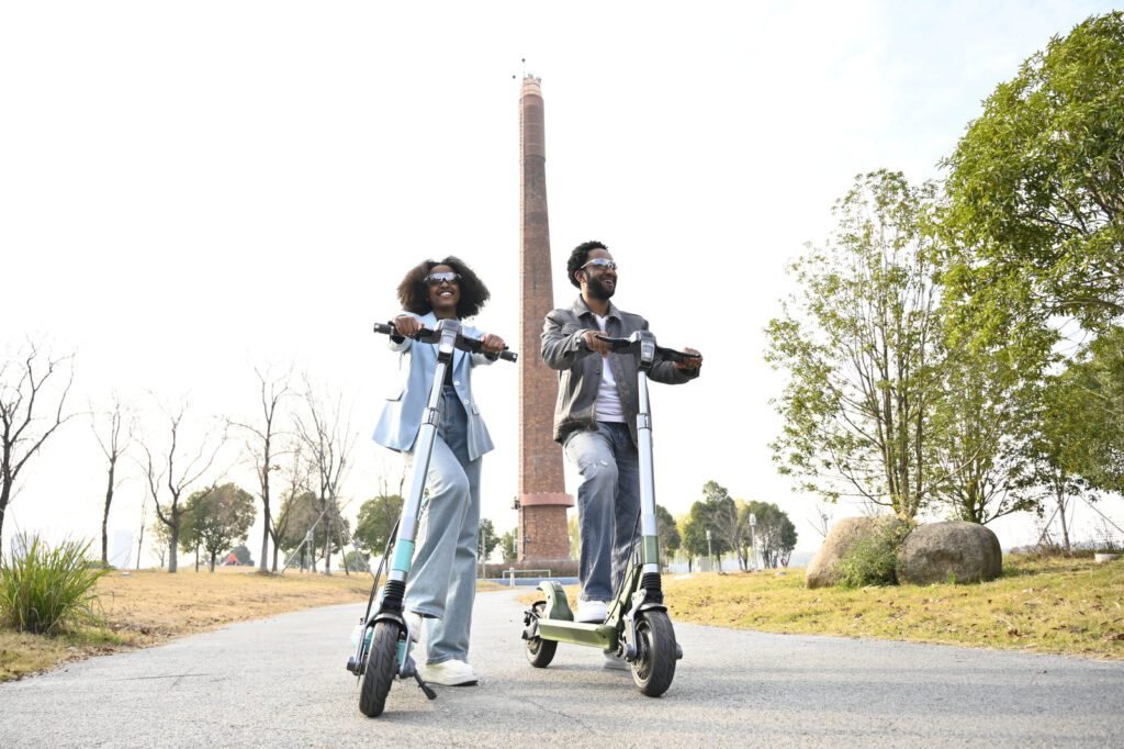 Two riders on TK3 electric scooters in a park