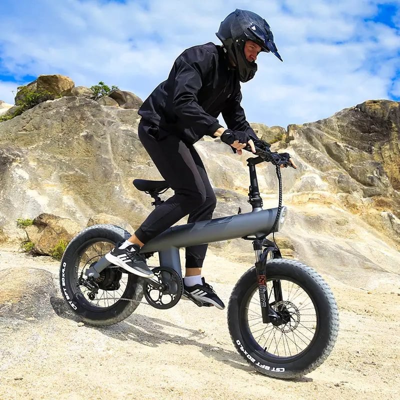 Rider standing on the pedals of the Q3 e-bike climbing a rock ledge
