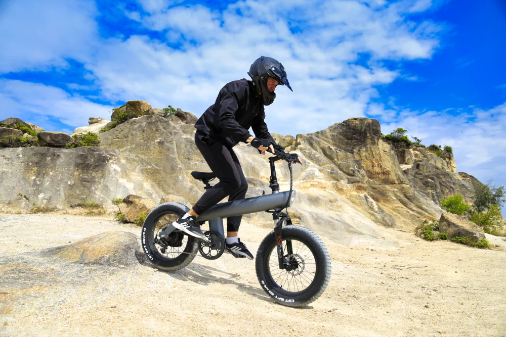 Rider on the Speedway Riders Q3 fat tire electric bike crossing a rocky trail