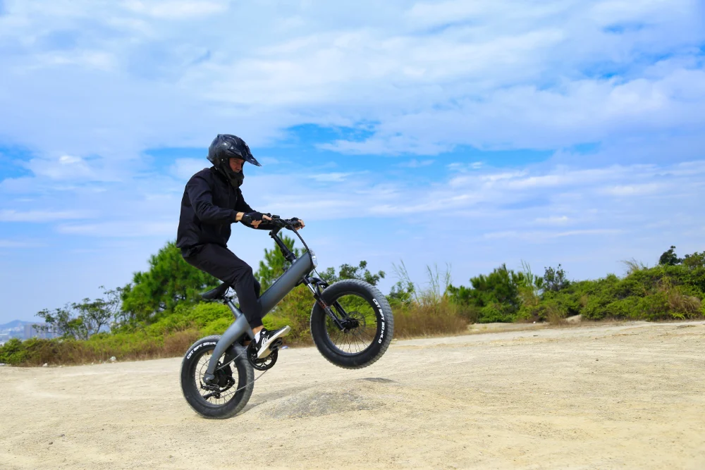 Rider lifting the front wheel of the Q3 fat tire e-bike on a dirt road